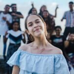 A cheerful teenage girl posing with friends in an outdoor setting, creating a joyful and lively atmosphere.