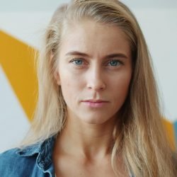 Close-up of a woman with blonde hair against a colorful geometric background.